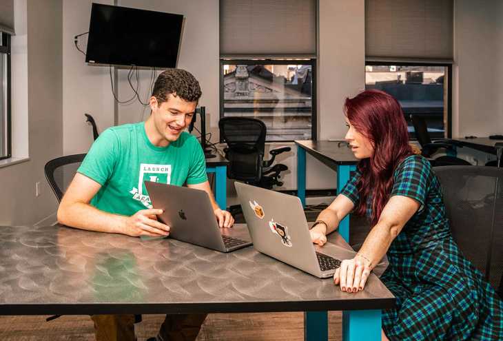 two students talking at a computer